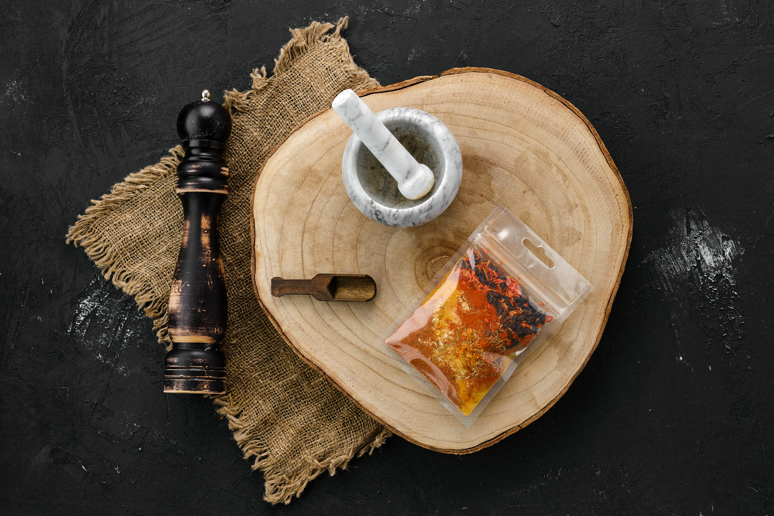 Wooden cross section with a set of spices for pilaf in plastic package and mortar and mill cara membuat bumbu bubuk sendiri